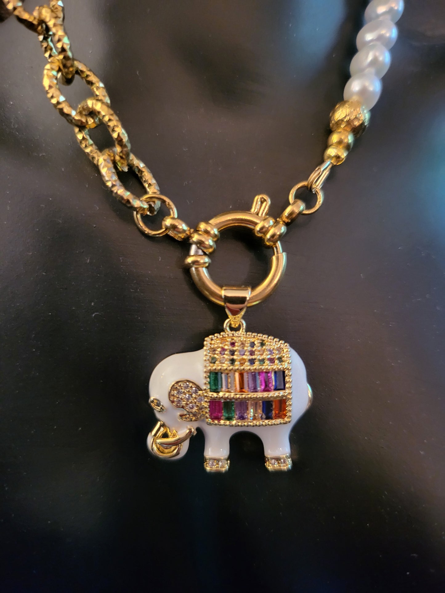 Collier Fantasia White avec pendentif éléphant laqué blanc, plaqué or, micropavé de cristaux multicolores, trèfles en nacre et perles de culture naturelles.