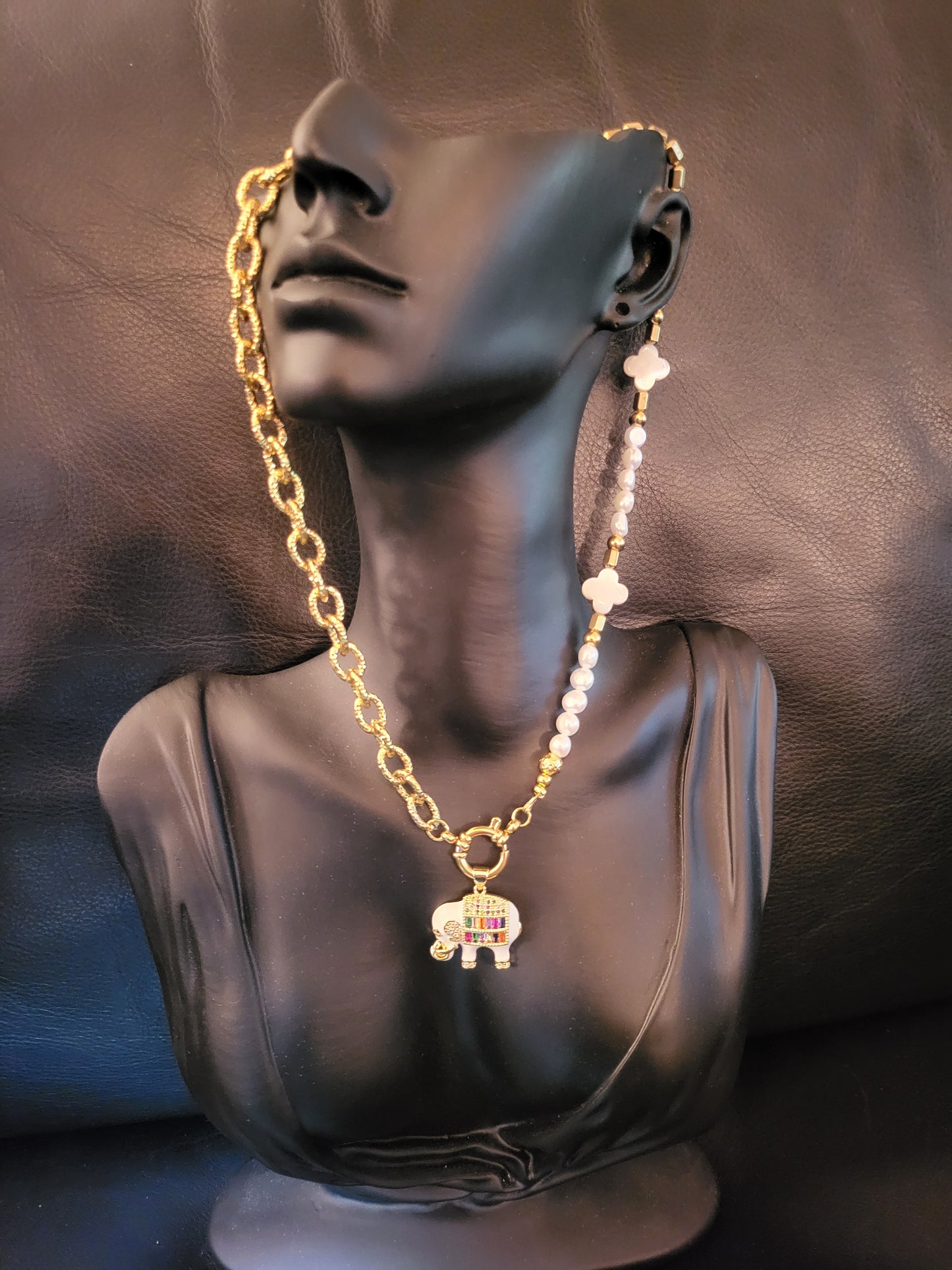 Collier Fantasia White avec pendentif éléphant laqué blanc, plaqué or, micropavé de cristaux multicolores, trèfles en nacre et perles de culture naturelles.